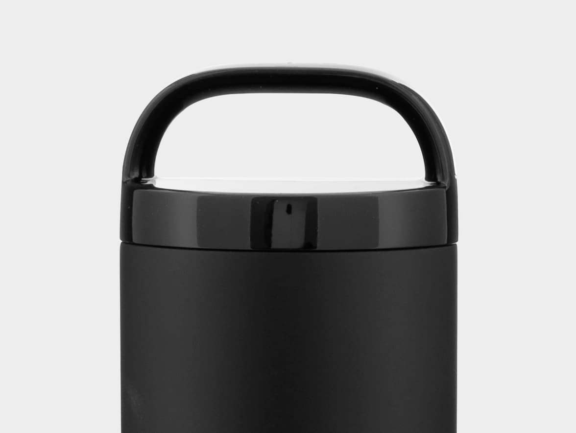 Top view of a matte black flask or bottle, featuring a shiny black lid with an integrated D-shaped handle, all against a plain light gray background.