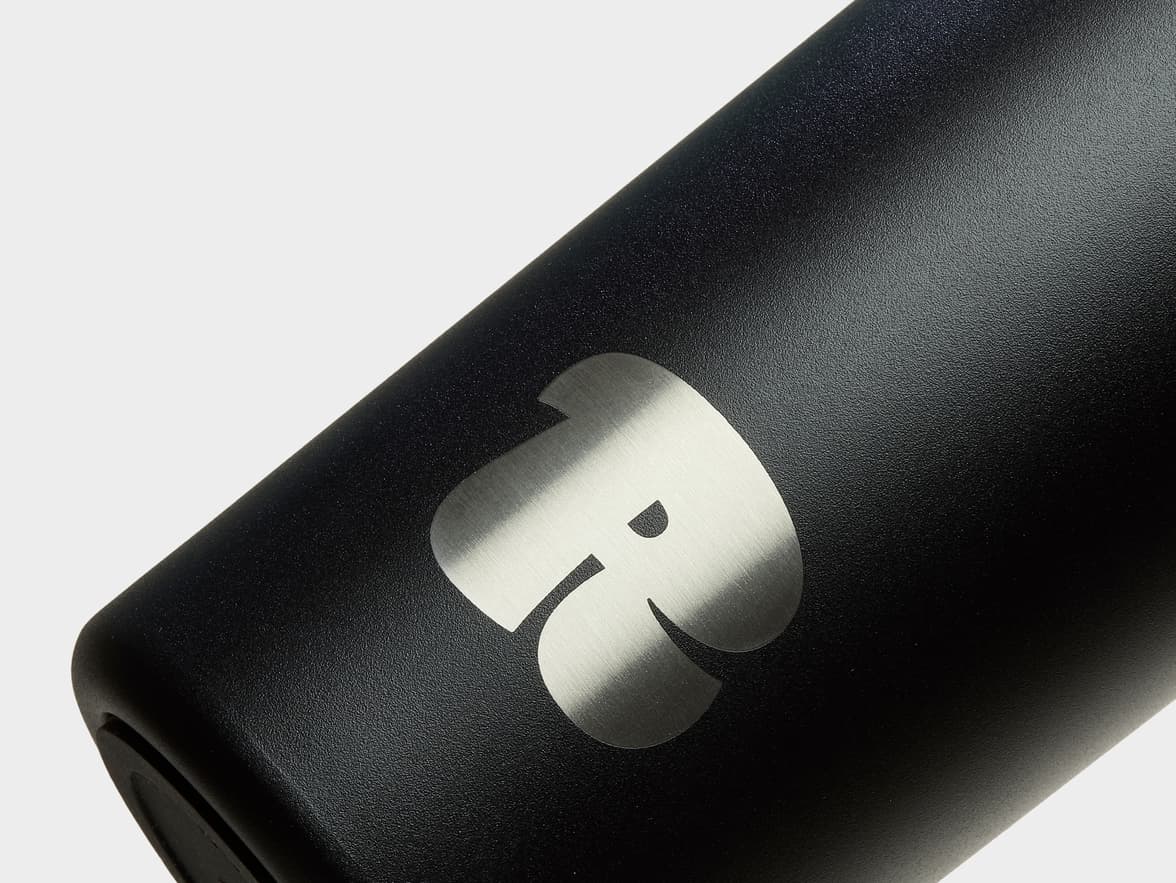 Detail image of silver custom branding on a jet black water bottle.