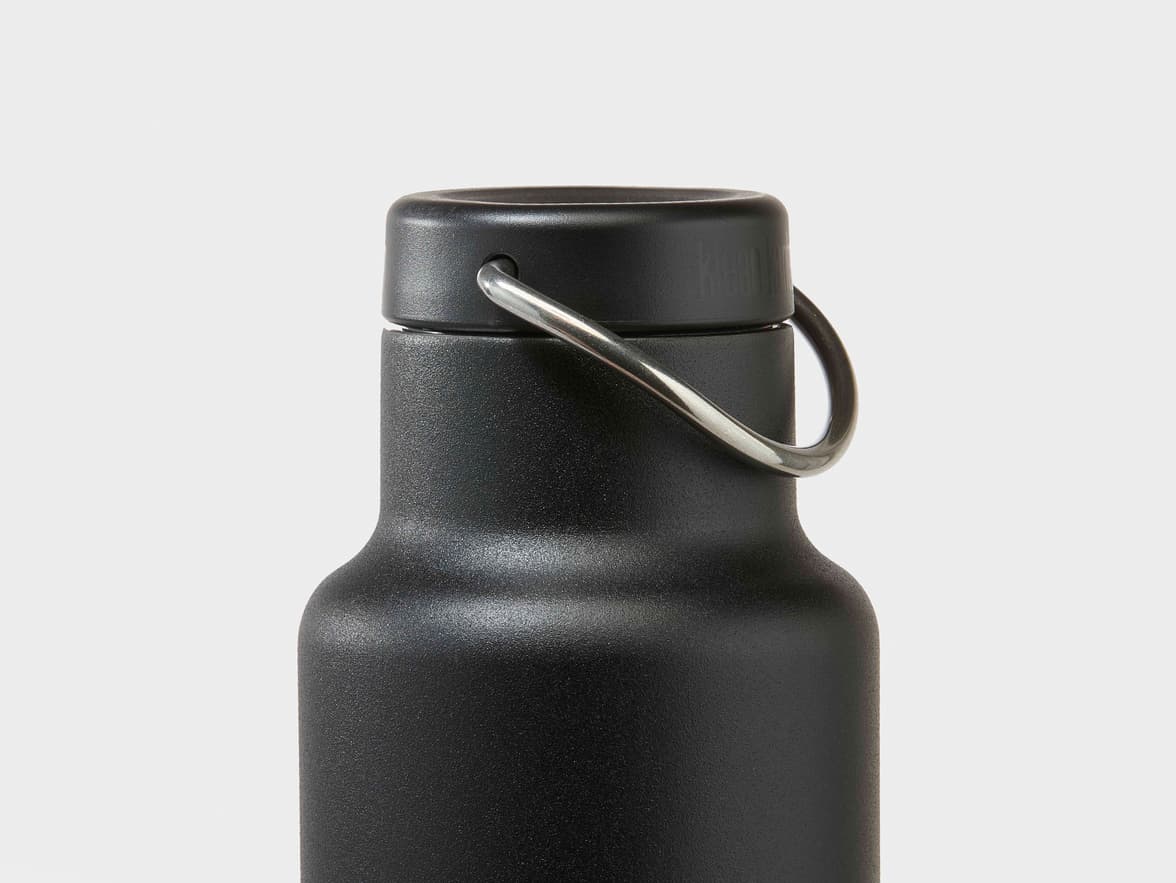 Close-up of a textured matte black Klean Kanteen water bottle with a metal loop on the cap.