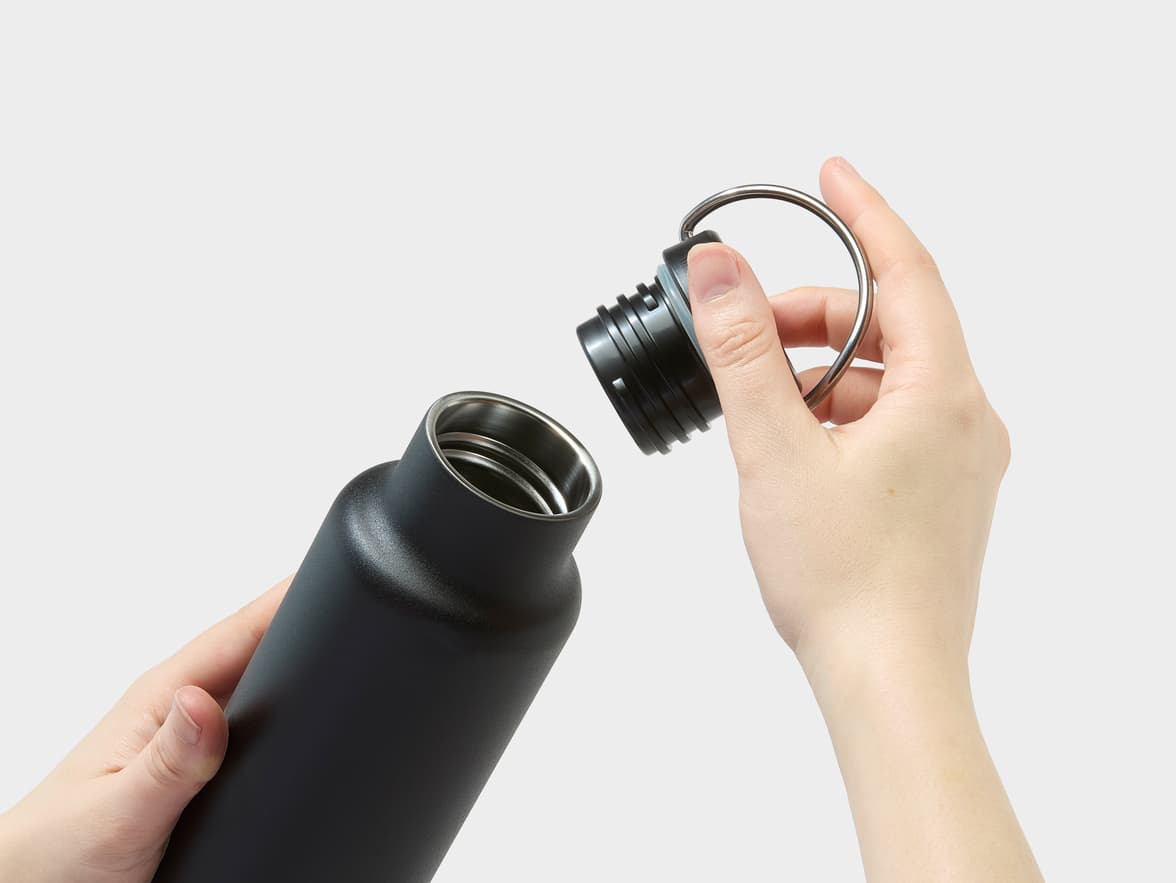 A person's hands opening a black water bottle.