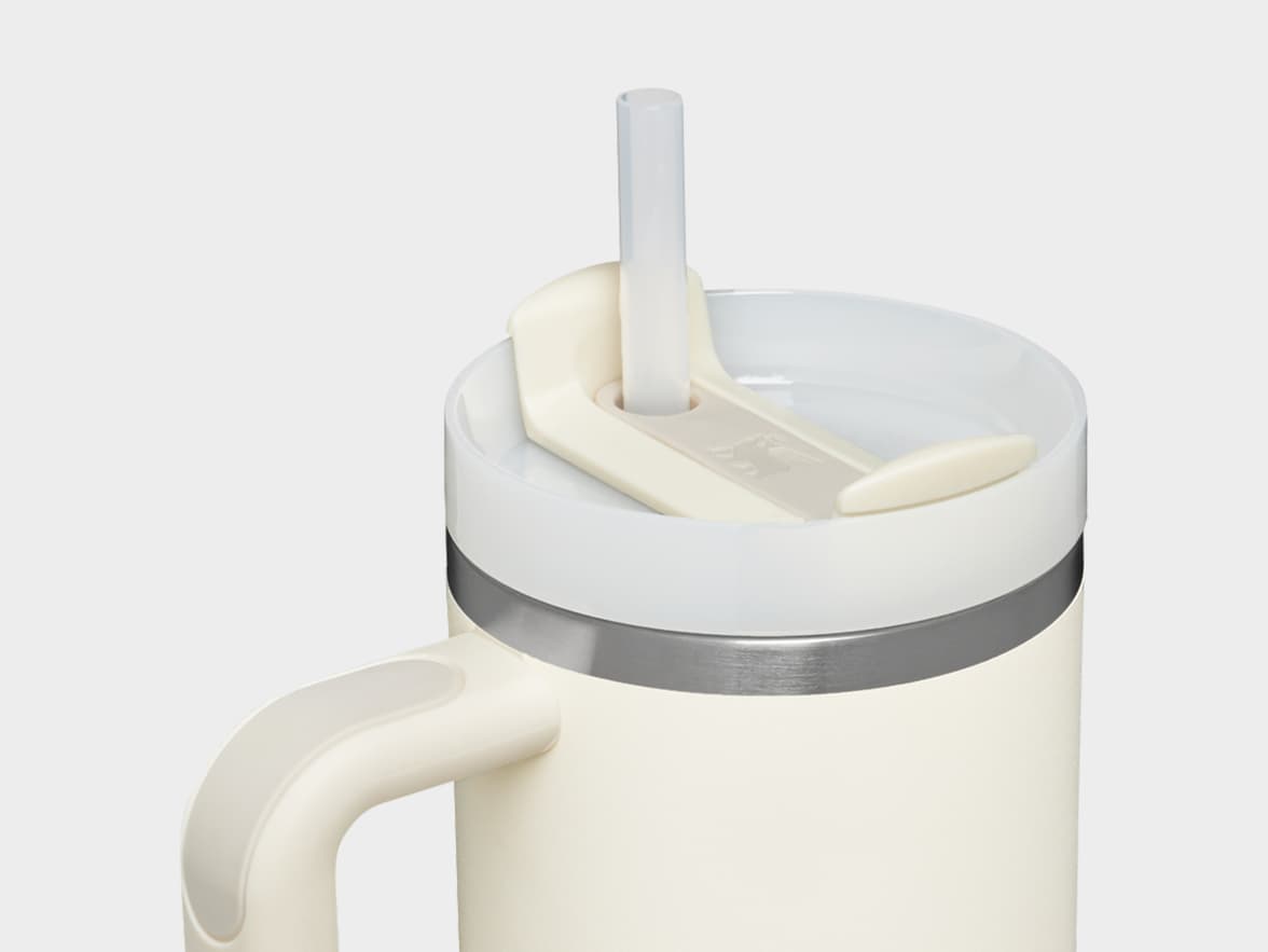 A cream-colored insulated tumbler with a white lid, clear straw, and handle.
