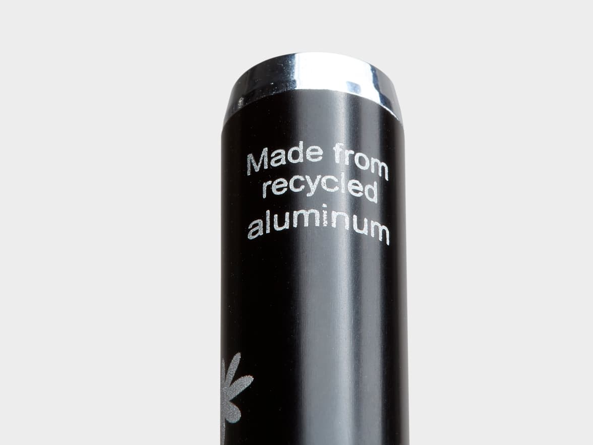 A black can with silver text that reads "Made from recycled aluminum" and a silver flower design.