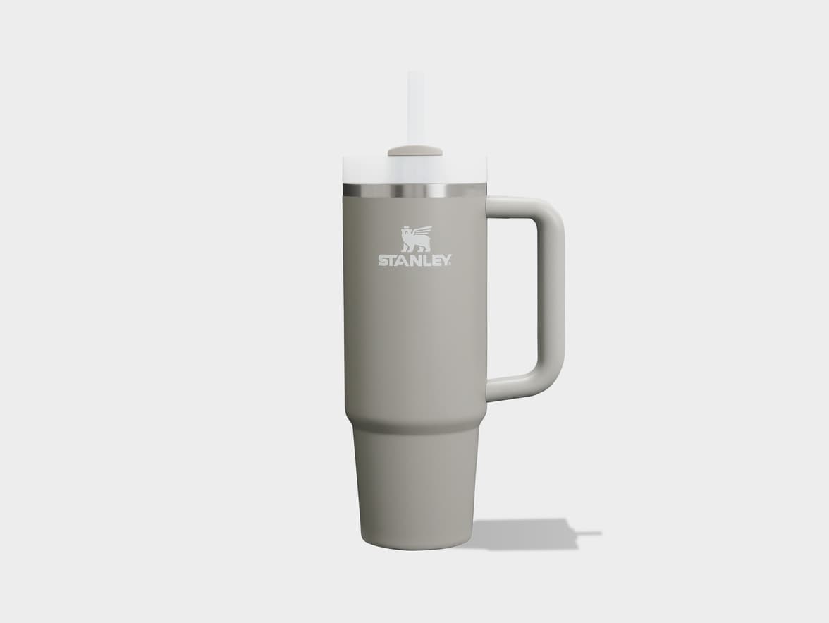 A light grey Stanley tumbler with a handle and straw on a plain background.