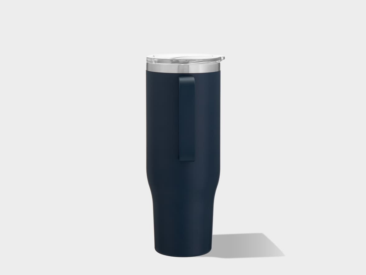 A dark blue tumbler with a clear lid and a side handle stands upright on a plain light gray background, casting a shadow to its right.