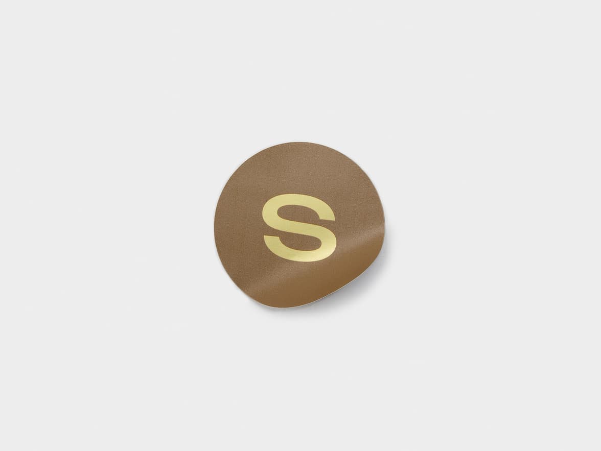 A round metallic sticker in gold and brown.