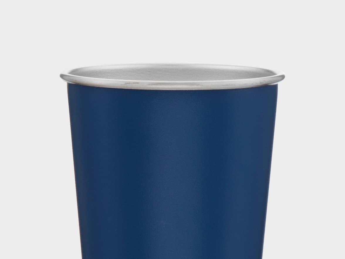 A close-up, centered shot of the top half of a dark blue, matte-finish cup with a silver-colored rim, against a plain light gray background.