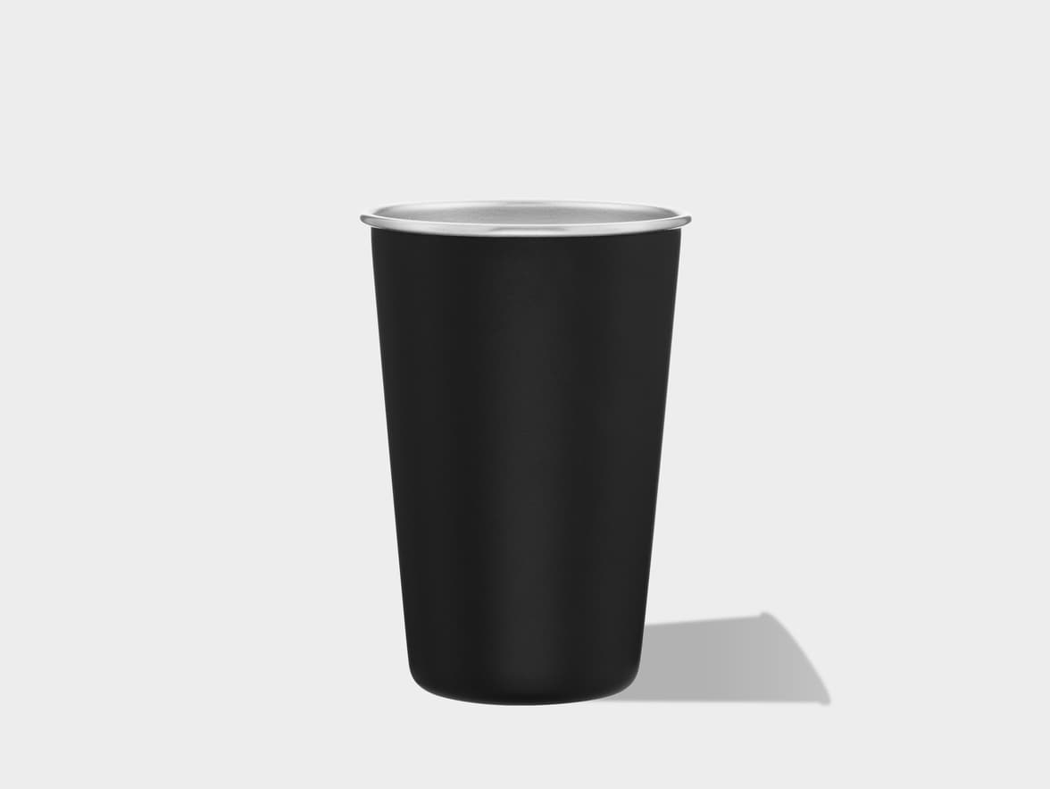 A tall, matte black cup with a silver rim, casting a shadow on a light grey background.