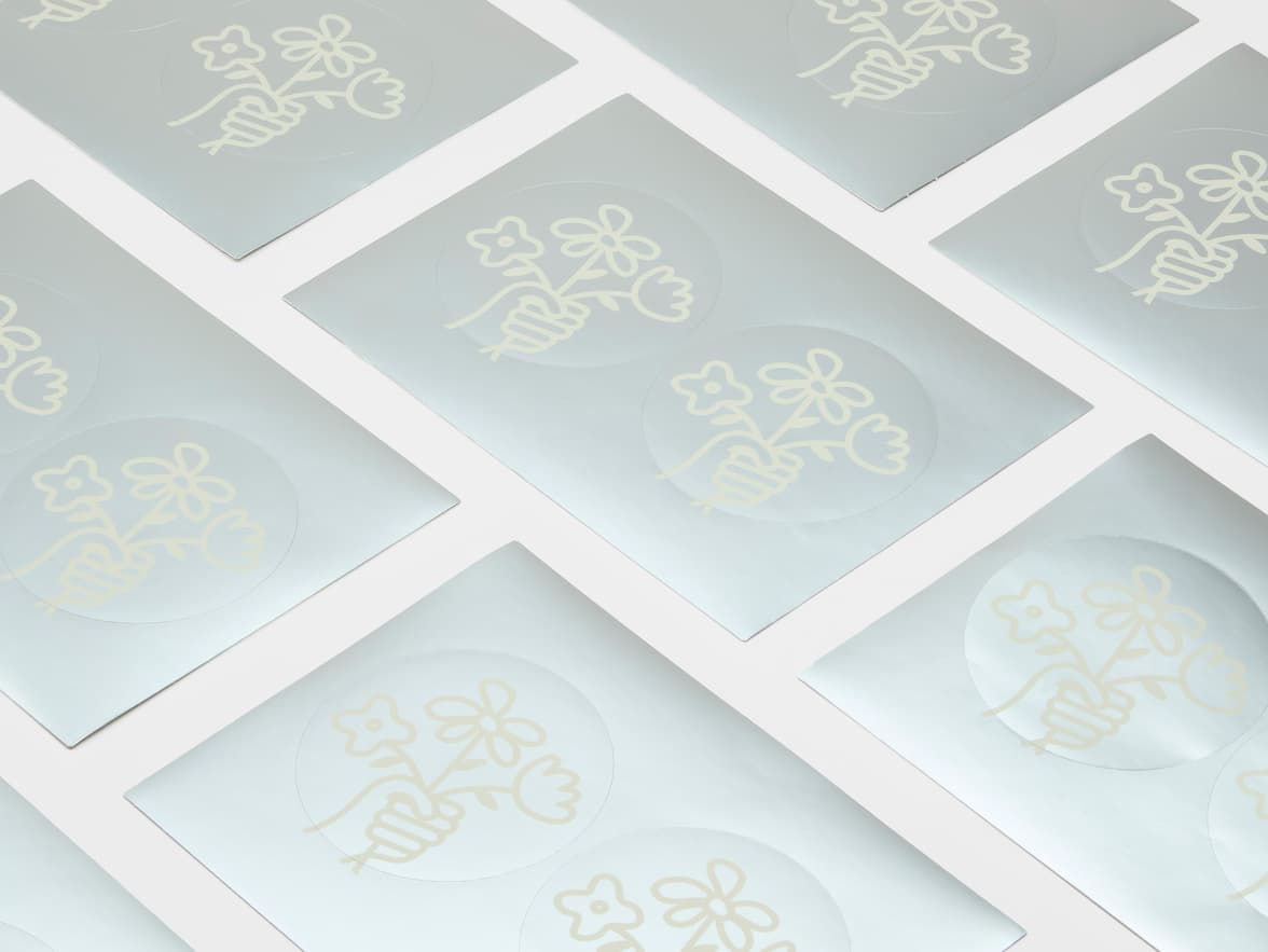 A collection of round silver metallic stickers with white customization.