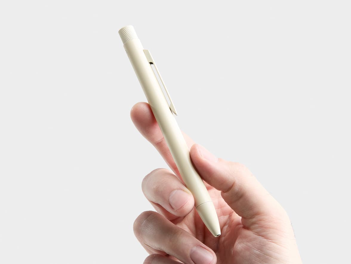 A hand holds a cream-colored pen with "CHINA" written on its clip.