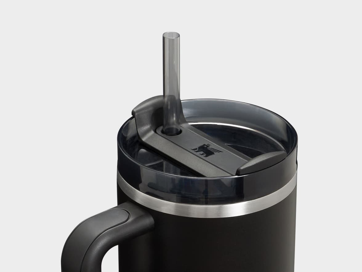 Close-up of a black Stanley tumbler with a clear lid, straw, handle, and logo.