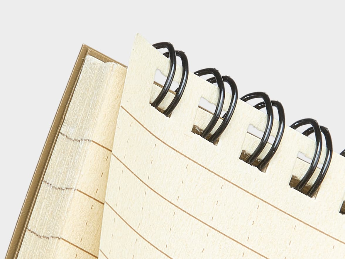 Open spiral notebook with creamy, dashed-and-lined paper and black spiral binding.