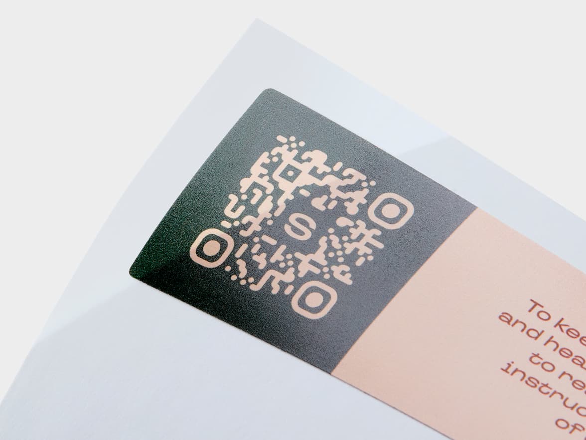 A close up image of a QR code printed onto a rectangular coated sticker.