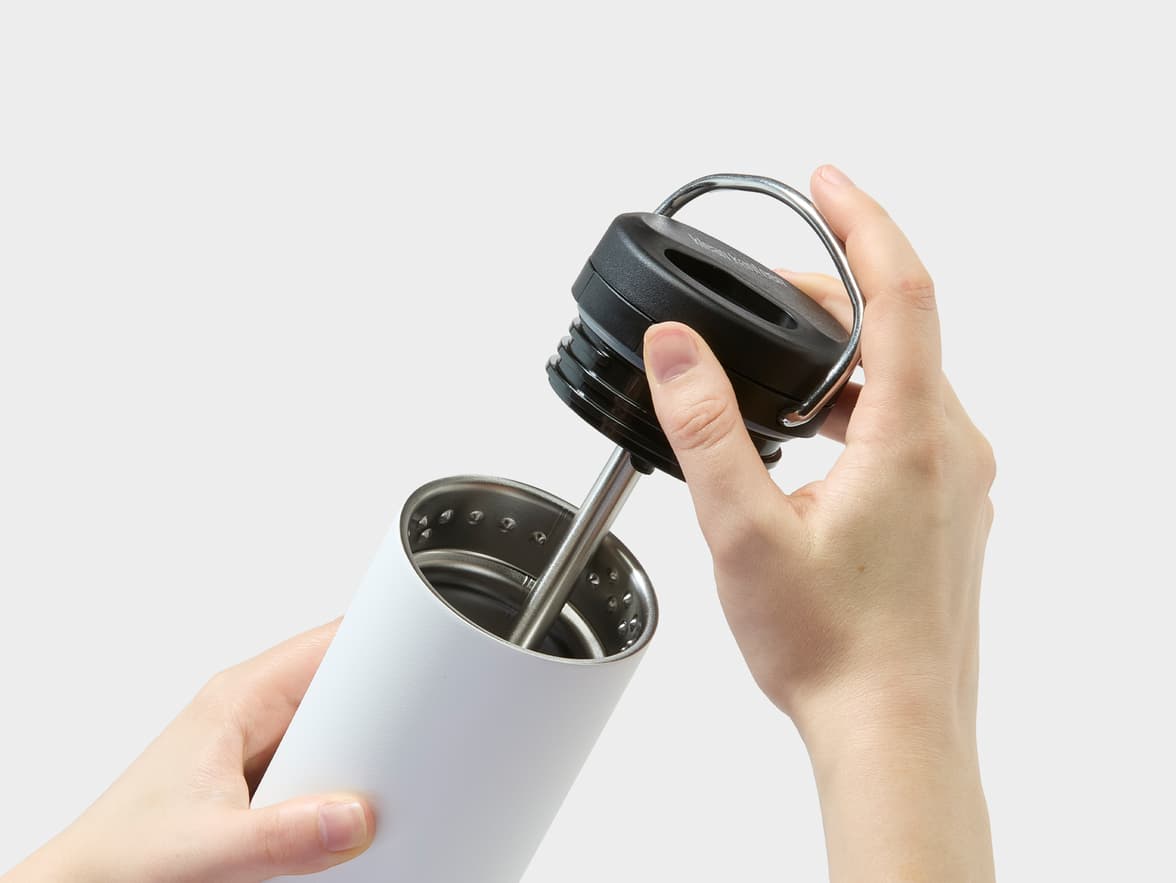 A person opening a white Klean Kanteen insulated bottle.