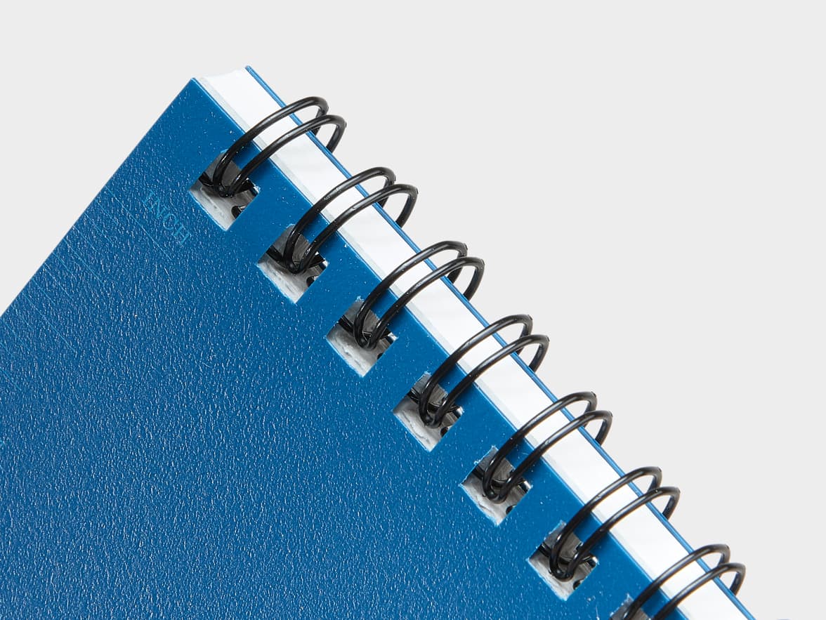Close-up of a blue spiral-bound notebook with 'NOTE' embossed on the cover.