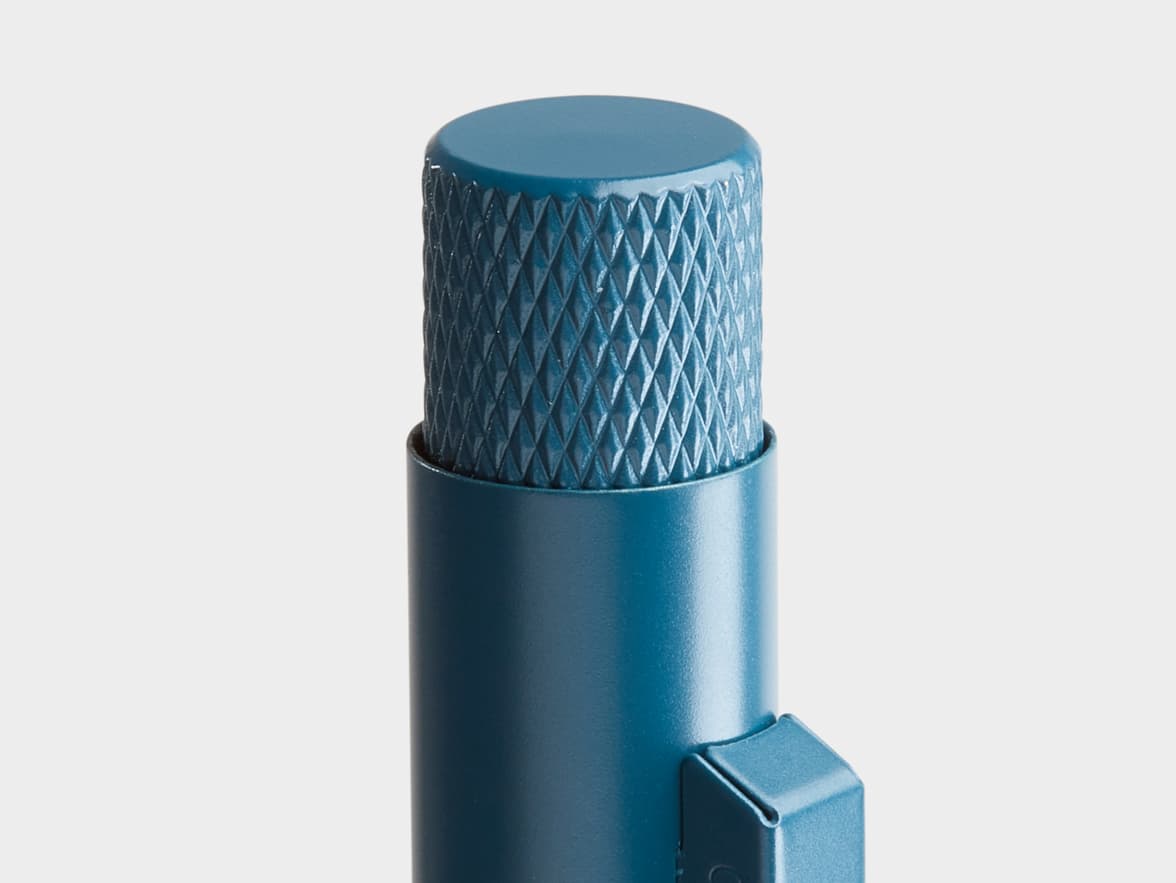 A close-up of the top portion of a teal pen, featuring a textured knurled cap and a smooth barrel with a clip.