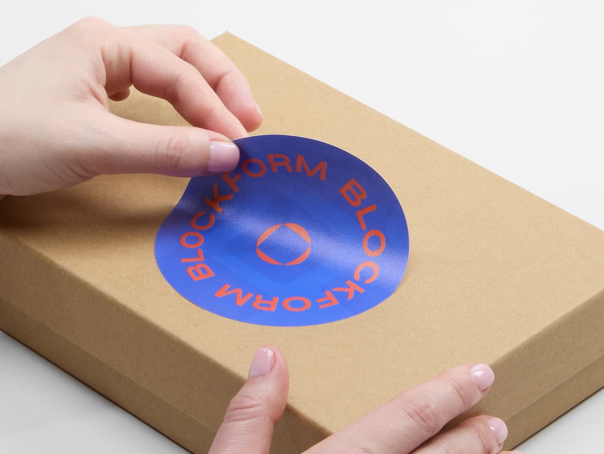 A person placing a customized matte paper sticker in size 4 inch on a cardboard box.
