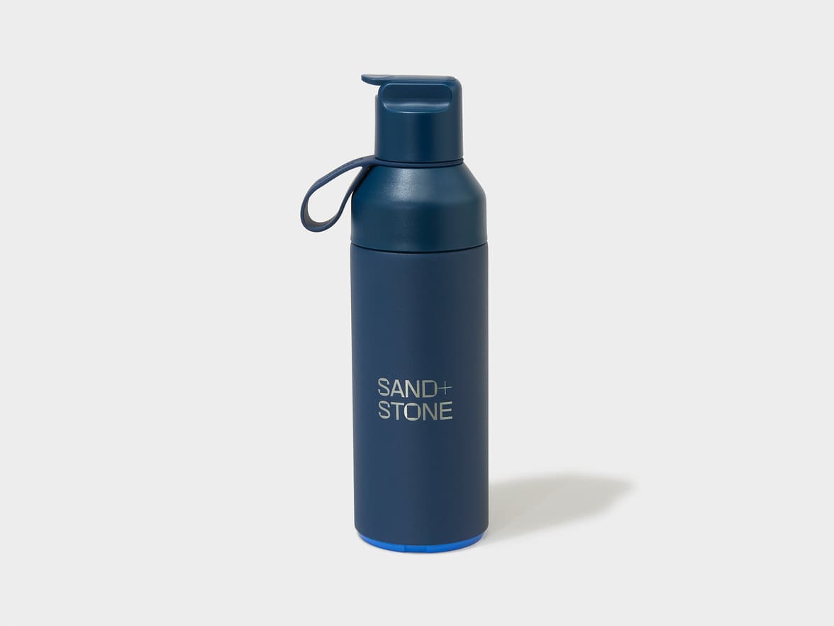 Navy blue insulated water bottle with "SAND+ STONE" branding.