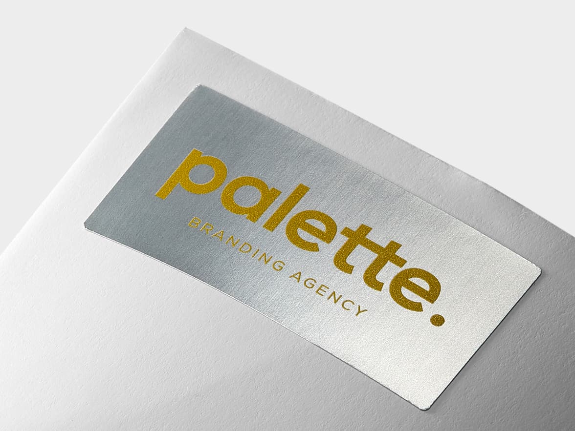 A close up of a silver rectangular metallic sticker with yellow branding.