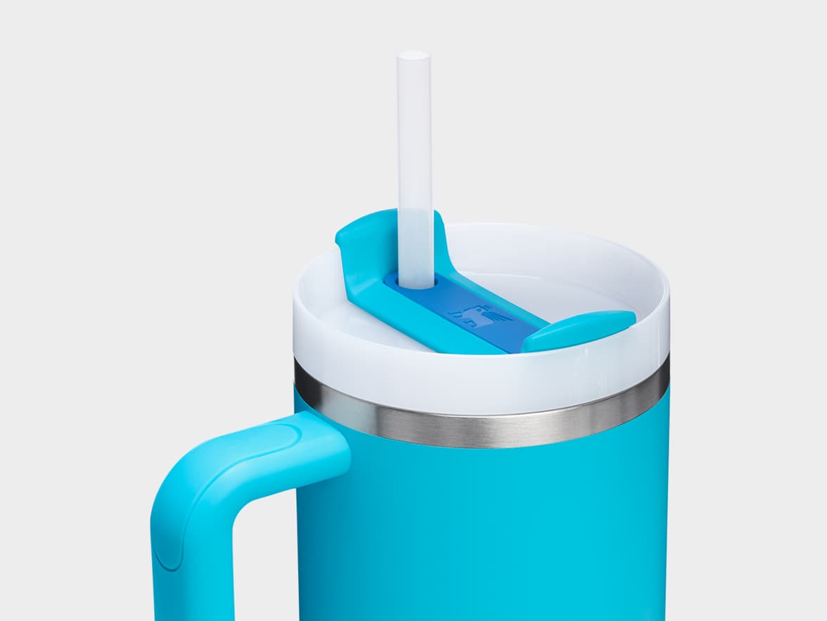 Blue travel mug with white lid, straw, and handle.