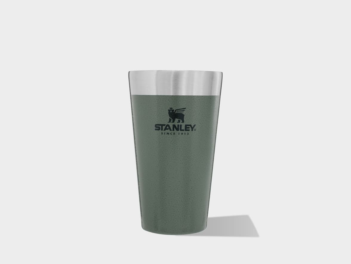 Green Stanley insulated tumbler with a silver rim and logo on a light background.