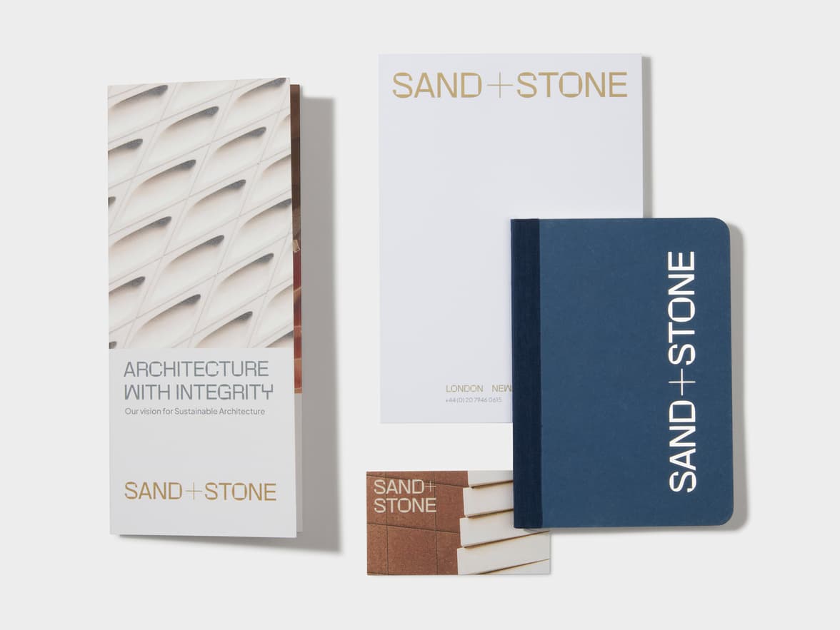 A set of SAND+STONE branded marketing materials and stationery.