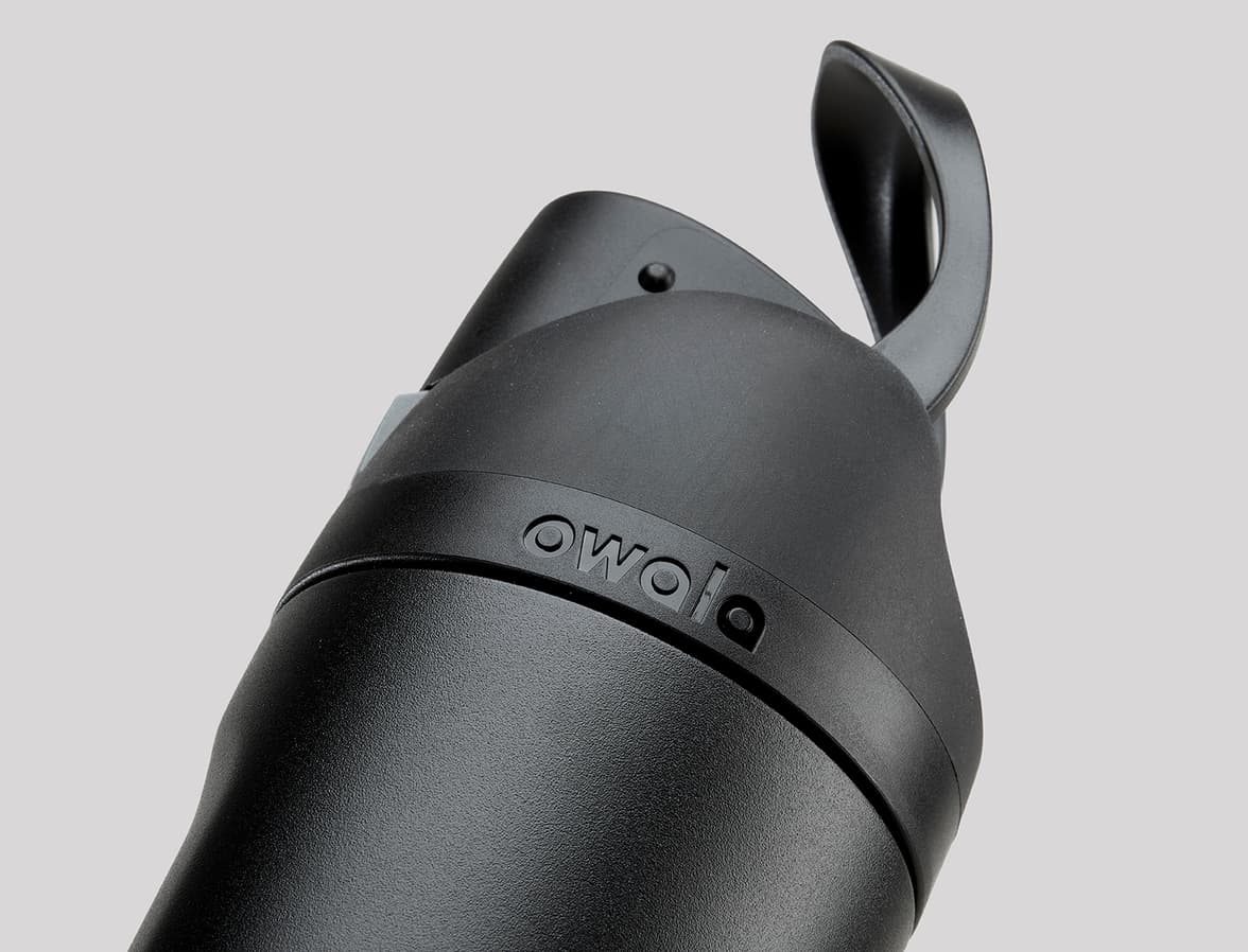 Close-up of the top of a black Owala water bottle with its lid open. The Owala logo is visible on the bottle.