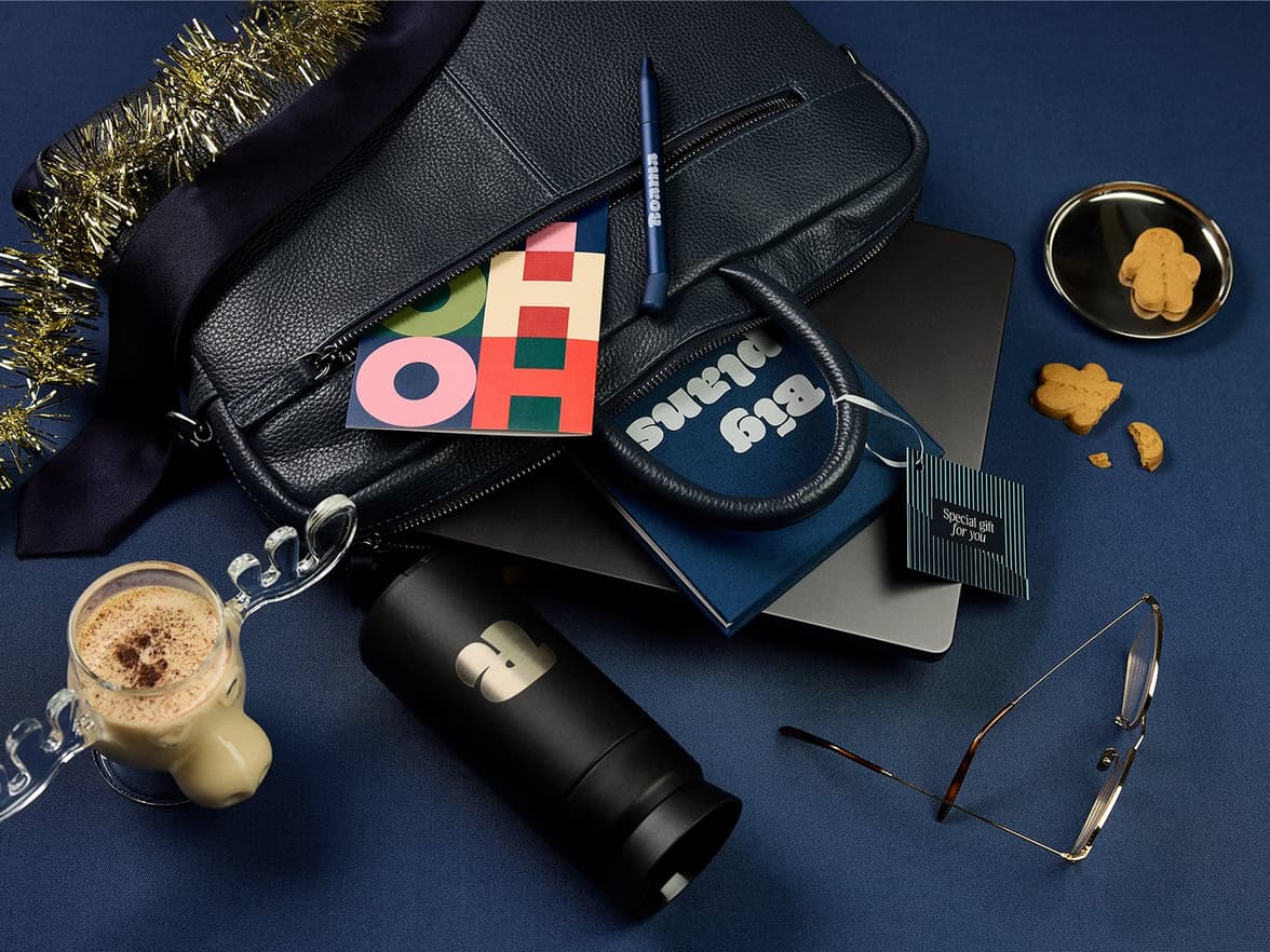 Varierty of branded merch laid out from a briefcase with tinsel & a reindeer with eggnog on the side