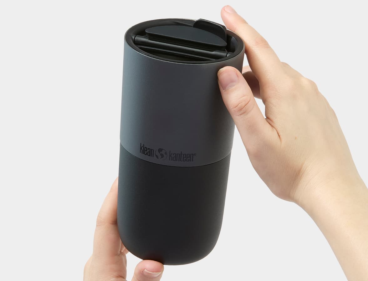 Hands holding a black Klean Kanteen tumbler.