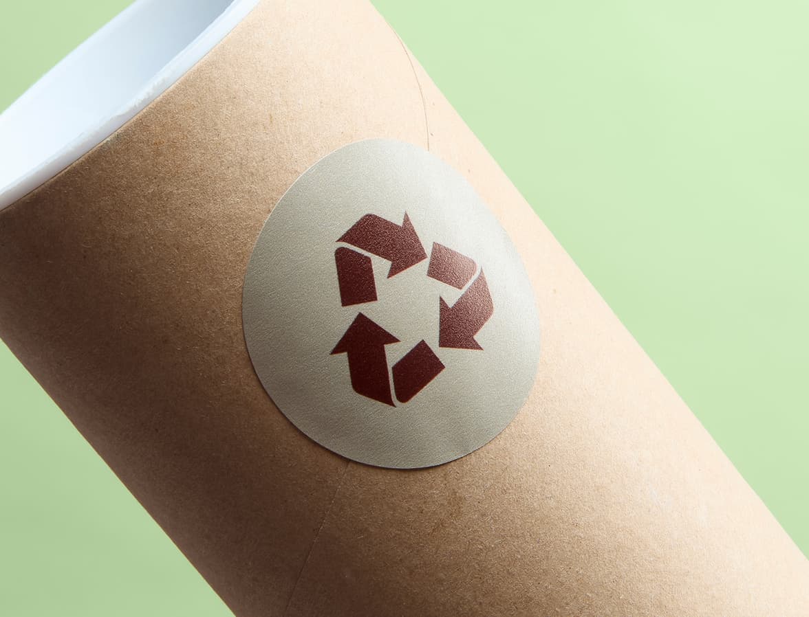 A matte paper sticker with the recycling symbol on it placed on a cardboard tube.