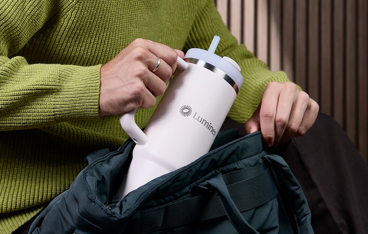 A person pulling a customized Stanley tumbler out of a bag.