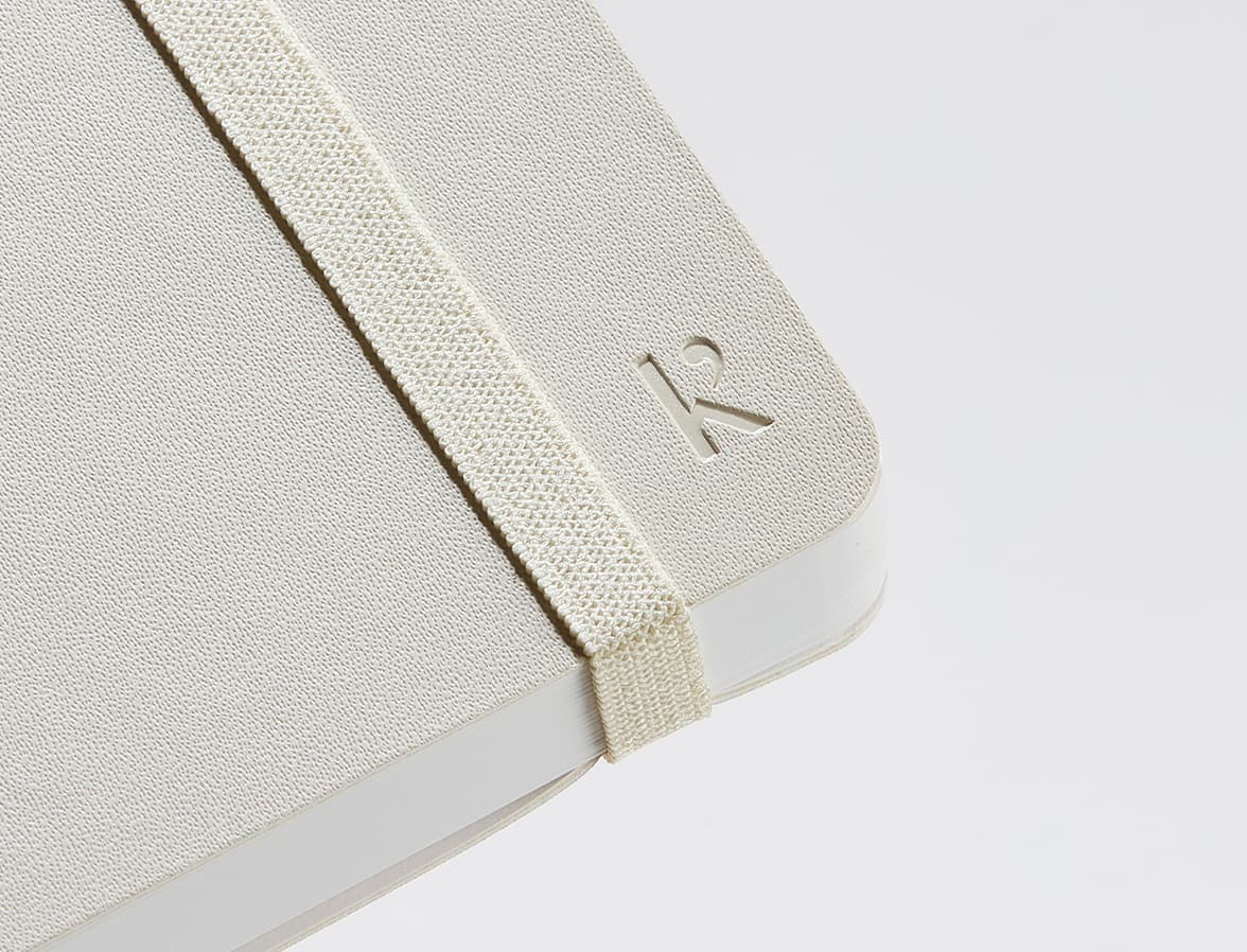 Corner of the Beige Karst Stone Paper Softcover Notebook showing the K branding and strap