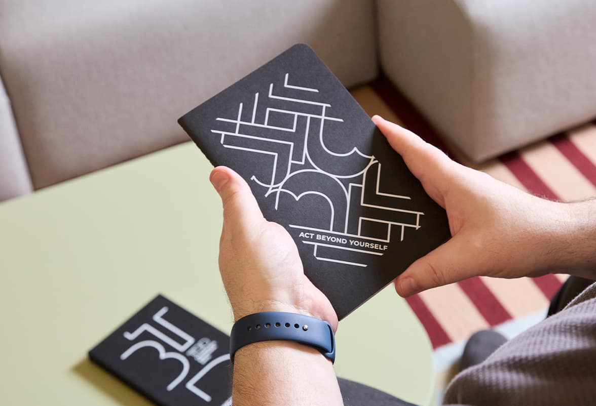 A person holding a jet black customized hardcover notebook.
