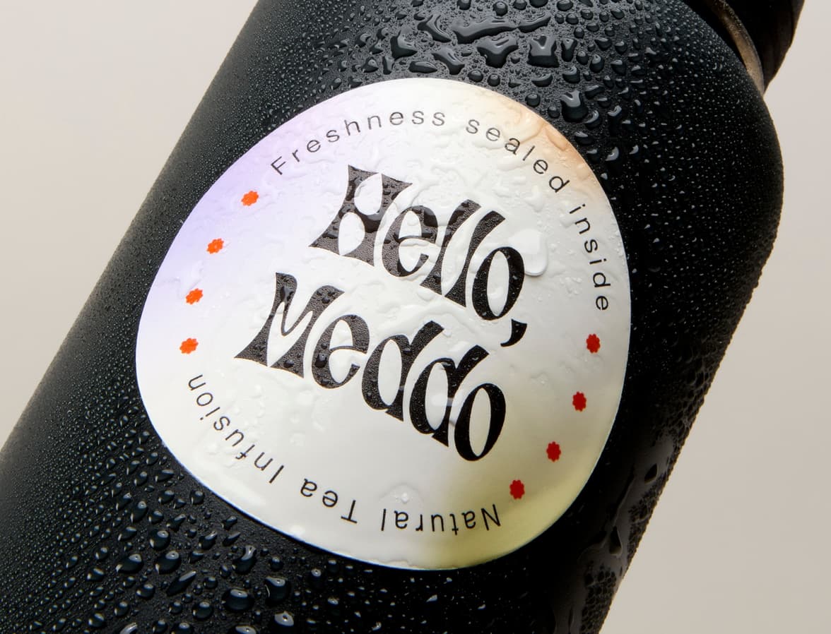 A detail image of a customized coated round sticker placed on a water bottle with water droplets on it.